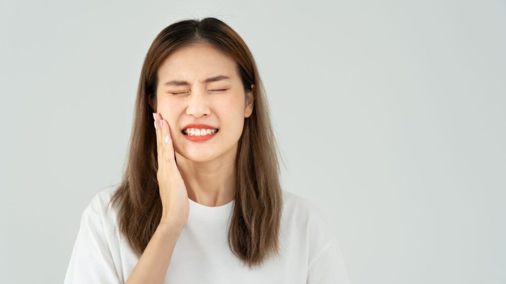 A woman holding her cheek from toothpain