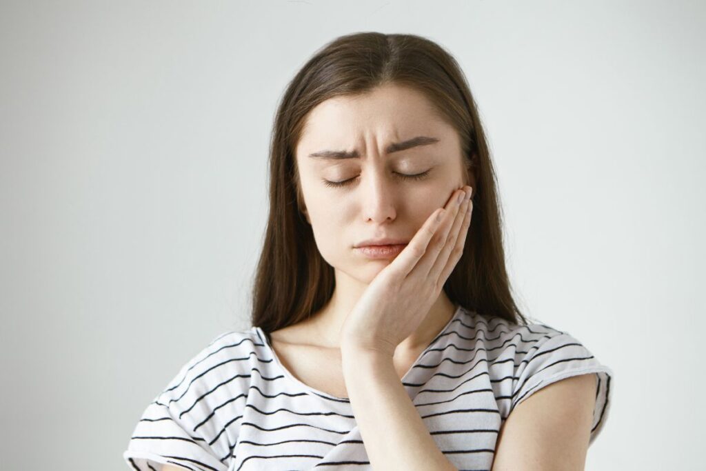 woman holding jaw area due to tooth ache